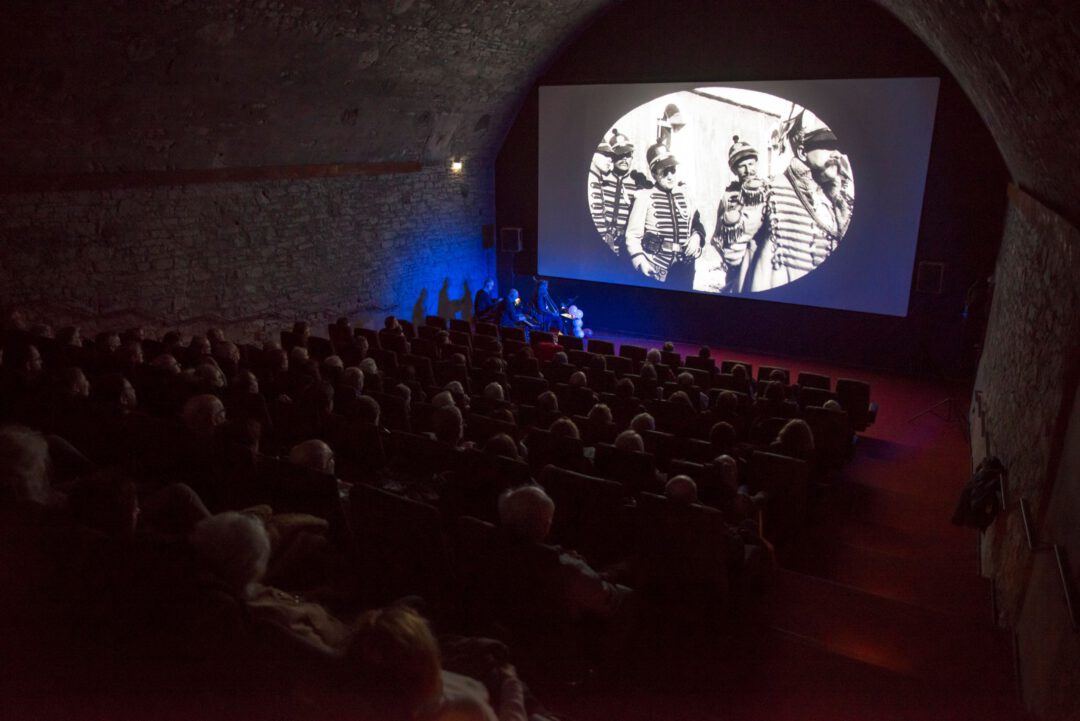 Viele Leute sitzen in einem Saal und schauen sich eine Aufführung im Rahmen der internatinalen Filmwoche an