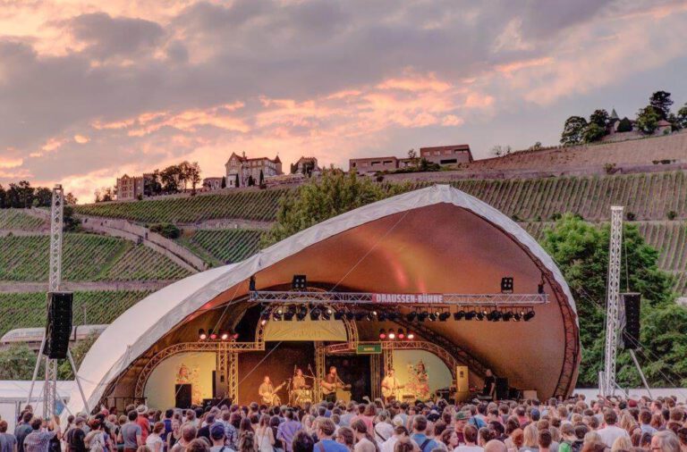 Bühne des Umsonst und Draußen Festivals im Dämmerlicht mit Weinbergen und Steinburg im Hintergrund