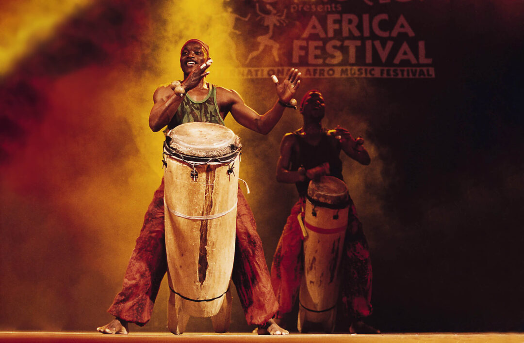 Zwei Männer spielen auf großen, länglichen Trommeln auf der Bühne des Africa Festivals