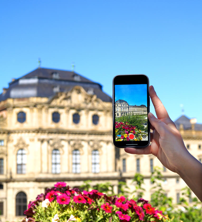 Tourist fotografiert Residenz Würzburg mit Smartphone