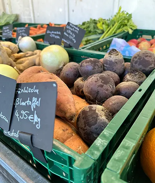 Ein Marktstand mit Gemüsekisten voller Kartoffeln und roter Beete auf dem Bauernmarkt in Würzburg-Lengfeld