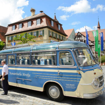 Ein blauer Omnibus im Retro-Stil steht vor einem historischen Gebäude