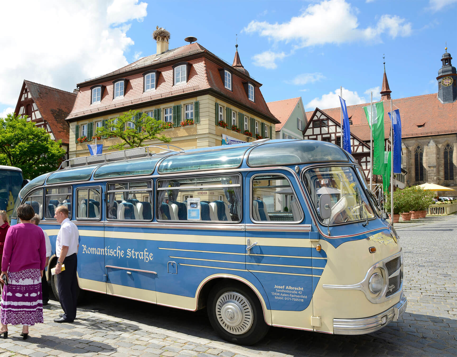 Ein blauer Omnibus im Retro-Stil steht vor einem historischen Gebäude