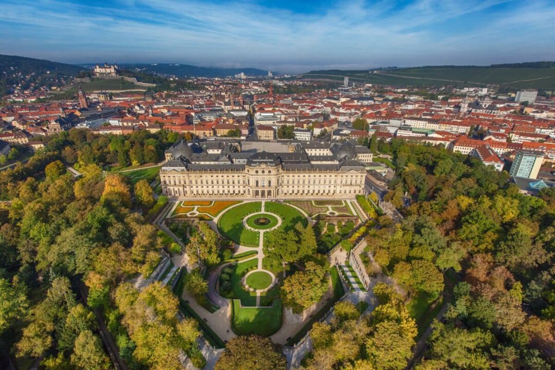 Die Würzburger Residenz und der Hofgarten aus der Vogelperspektive. Im Hintergrund ist die komplette Stadt zu sehen.